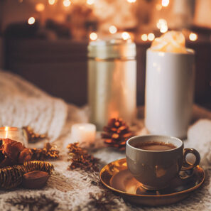 Cozy winter or autumn morning at home. Swedish hygge includes hot coffee with a gold metallic spoon, a warm blanket and candle lights.